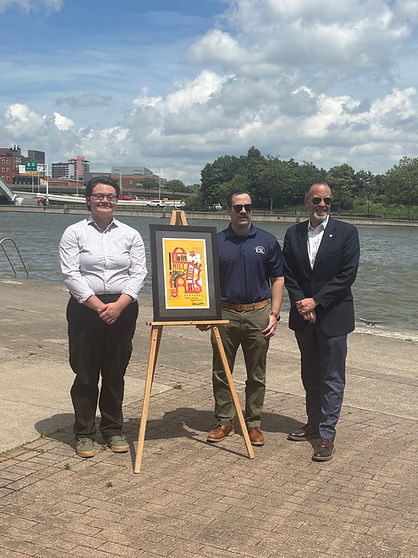 Finneas Button standing next to his Corn Hill Poster, and two Corn Hill officials