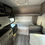 Thumbnail: Interior view of a RV with a bed, stove, and seating area.