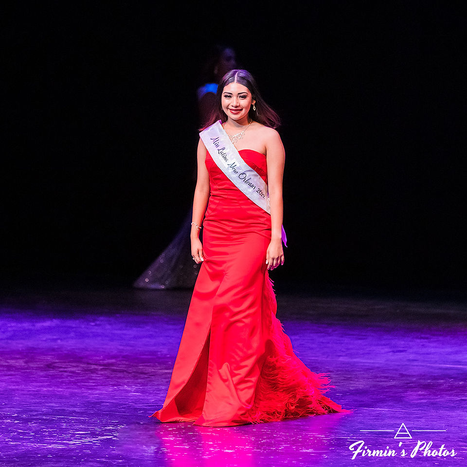 Woman standing on stage and smiling while wearing a red dress
