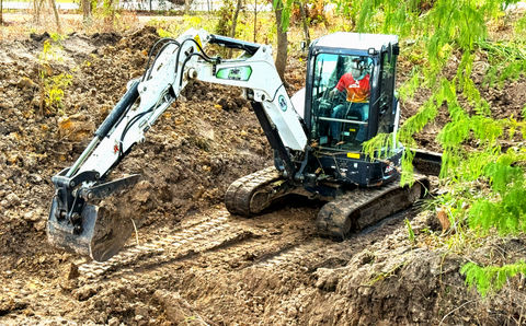 Mini excavator digging soil, a construction site. Land clearing near me.