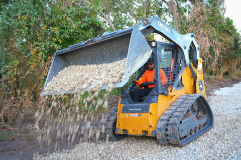 John Deere skid steer dumping gravel on path, construction site. land clearing near me