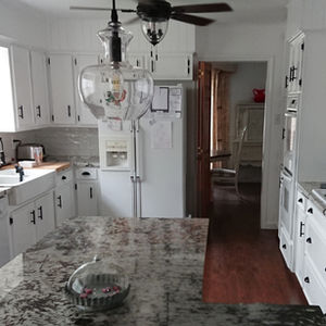Modern kitchen with granite island and hanging light.