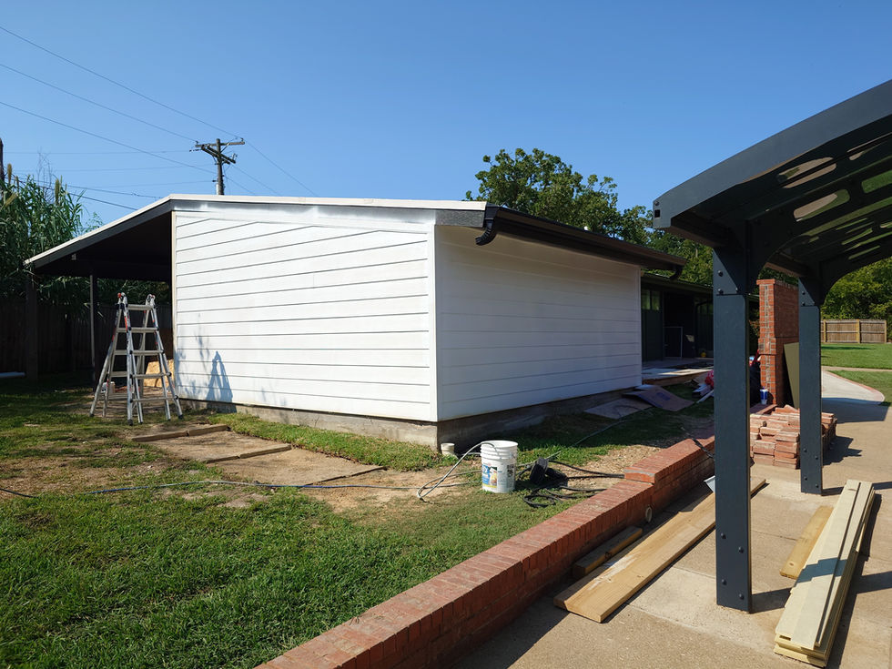 White building with ladder and tools outside.