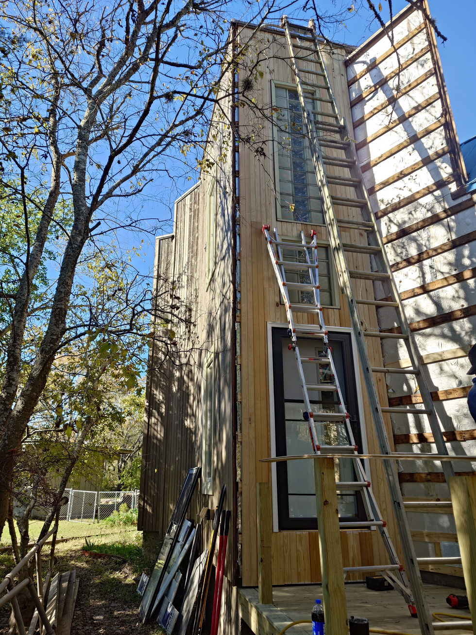 Tall building under construction with ladders and trees.