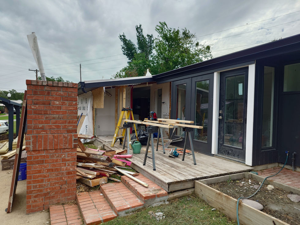 Construction site with tools and materials outside building.