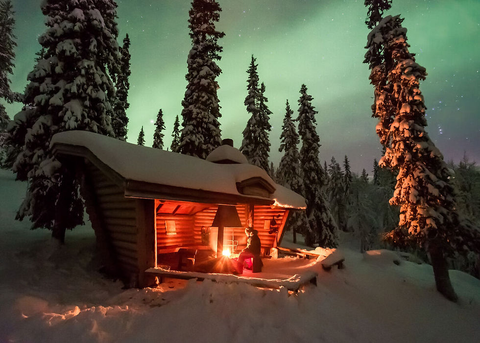 Cottage en laponie finlandaise sous la neige en pleine forêt avec vue sur les aurores boréales.
