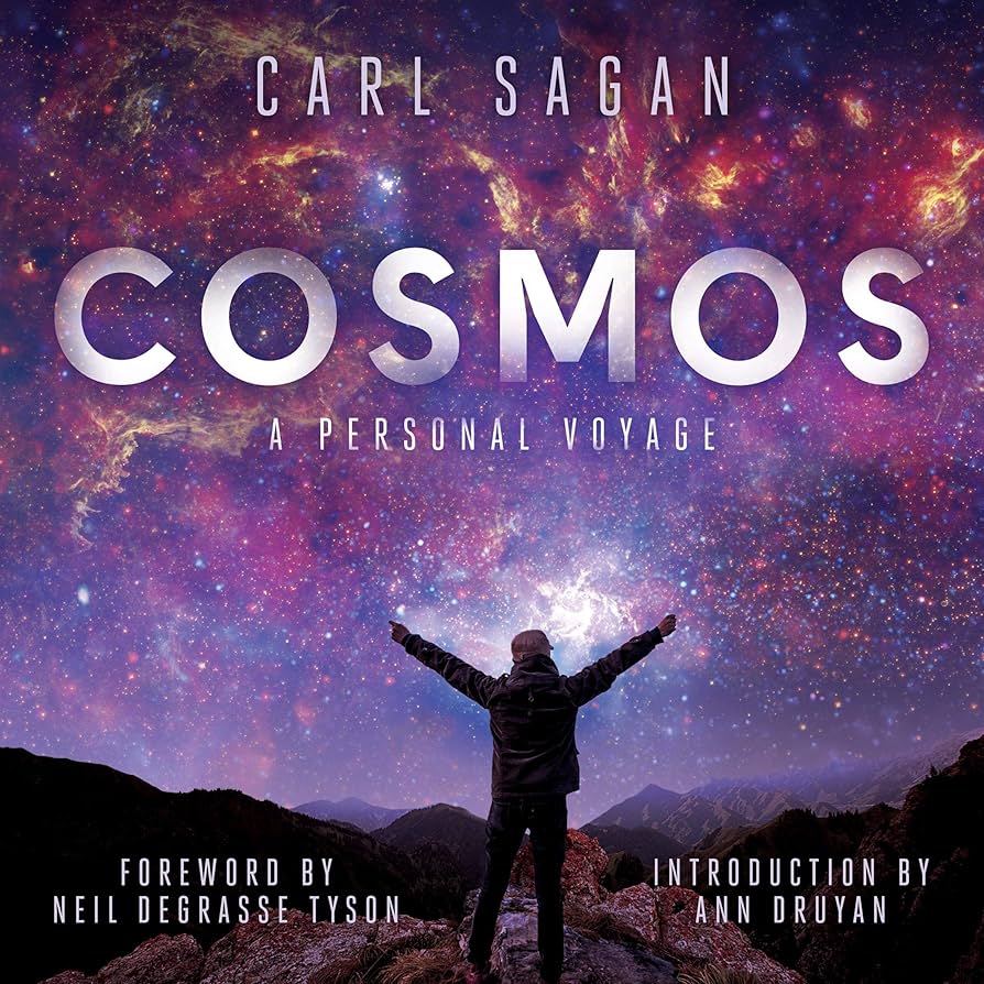 Audiobook cover for “Cosmos: A Personal Voyage” by Carl Sagan. Silhouetted figure with arms raised stands before a vibrant purple and pink nebula-filled night sky. Large silver metallic title text. Includes foreword by Neil deGrasse Tyson and introduction by Ann Druyan.
