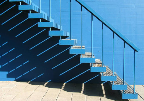 Immagine che rappresenta una scala blu che sale, con un'ombra proiettata sotto di essa. Simboleggia il percorso di crescita e sviluppo personale attraverso la terapia cognitivo-comportamentale, enfatizzando il concetto di progressione e cambiamento