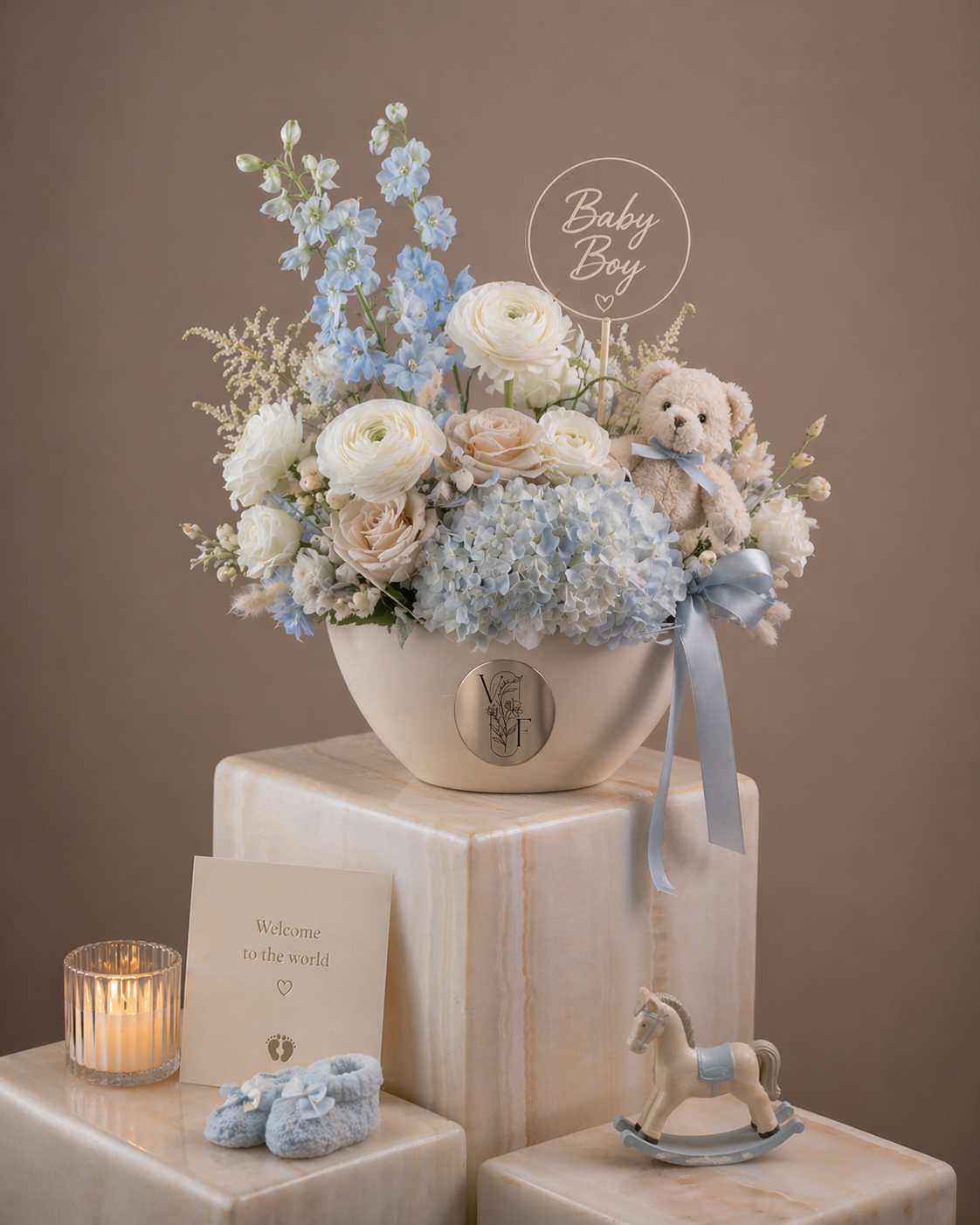 Soft blue and white floral arrangement with a teddy bear in a decorative vase