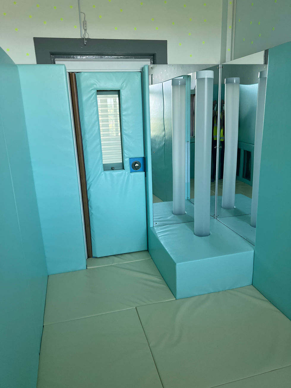 a chroma tube and plinth with mirrors complimented by pale blue wall padding and a cream padded floor