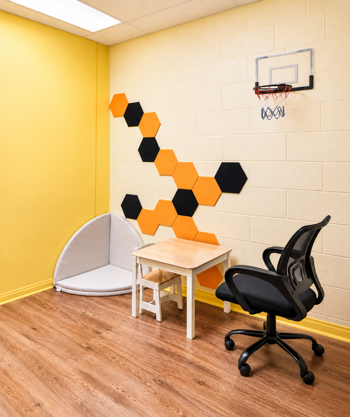 Una sala de terapia en nuestra clínica de Van Nuys con una mesa infantil, una colchoneta suave en la esquina y paneles de pared en forma de panal
