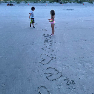 Kids standing near hearts drawn in the sand on the beach in Atlantic Beach, Florida.