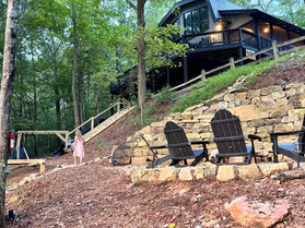 Exterior of Lake Dakwa Lodge, a family-friendly cabin in Ellijay, Georgia, with hillside firepit and outdoor play area.