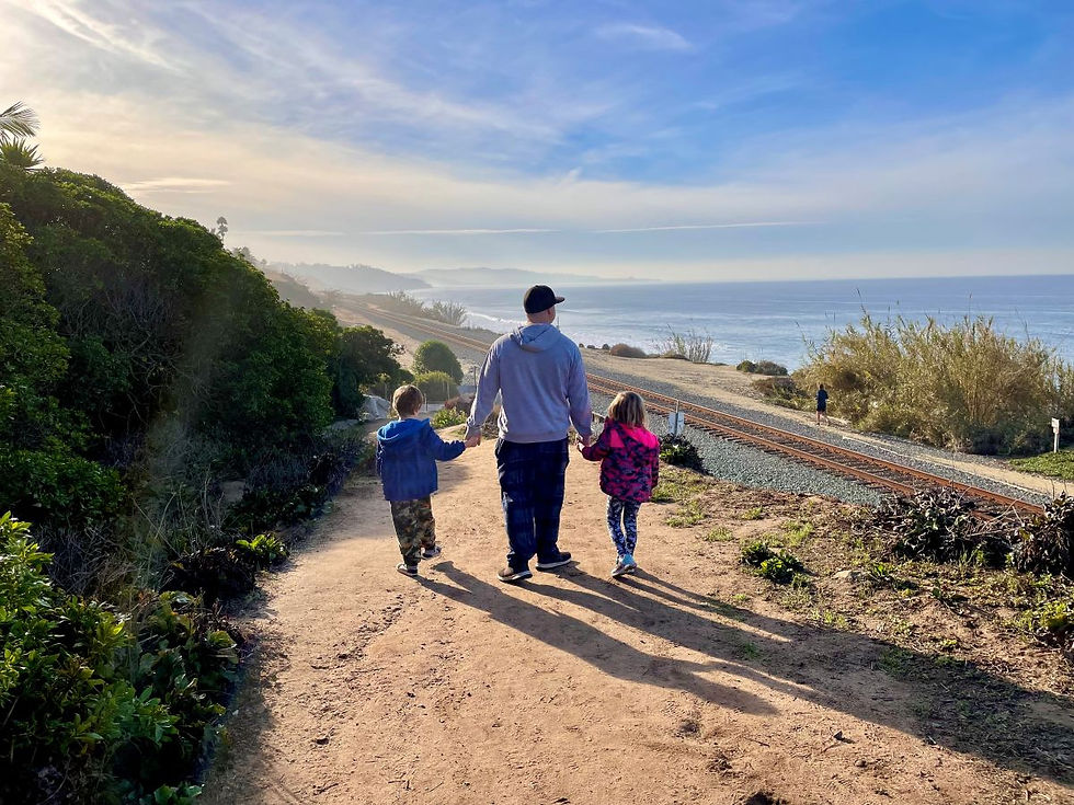 Family walking along a coastal trail with ocean views in Del Mar California.