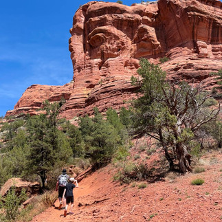 Family hiking beneath red rock cliffs in Sedona, Arizona.