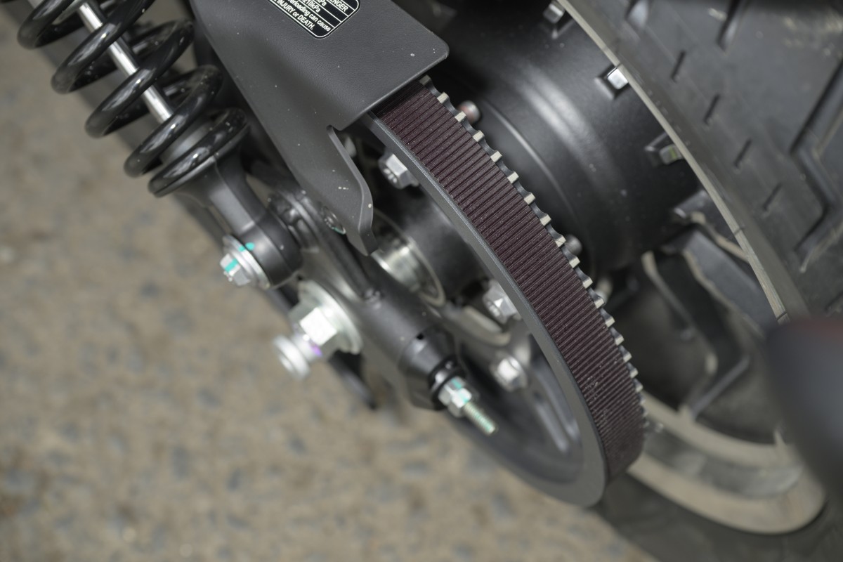 QJMOTOR SRV 600 V2: Detail des breiten Zahnriemens und seines Antriebsrads neben dem Rahmen.
