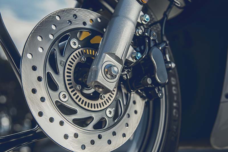 QJMOTOR SQ16 125: Nahaufnahme der gelochten vorderen Bremsscheibe mit ABS-Sensorring an der Gabel.