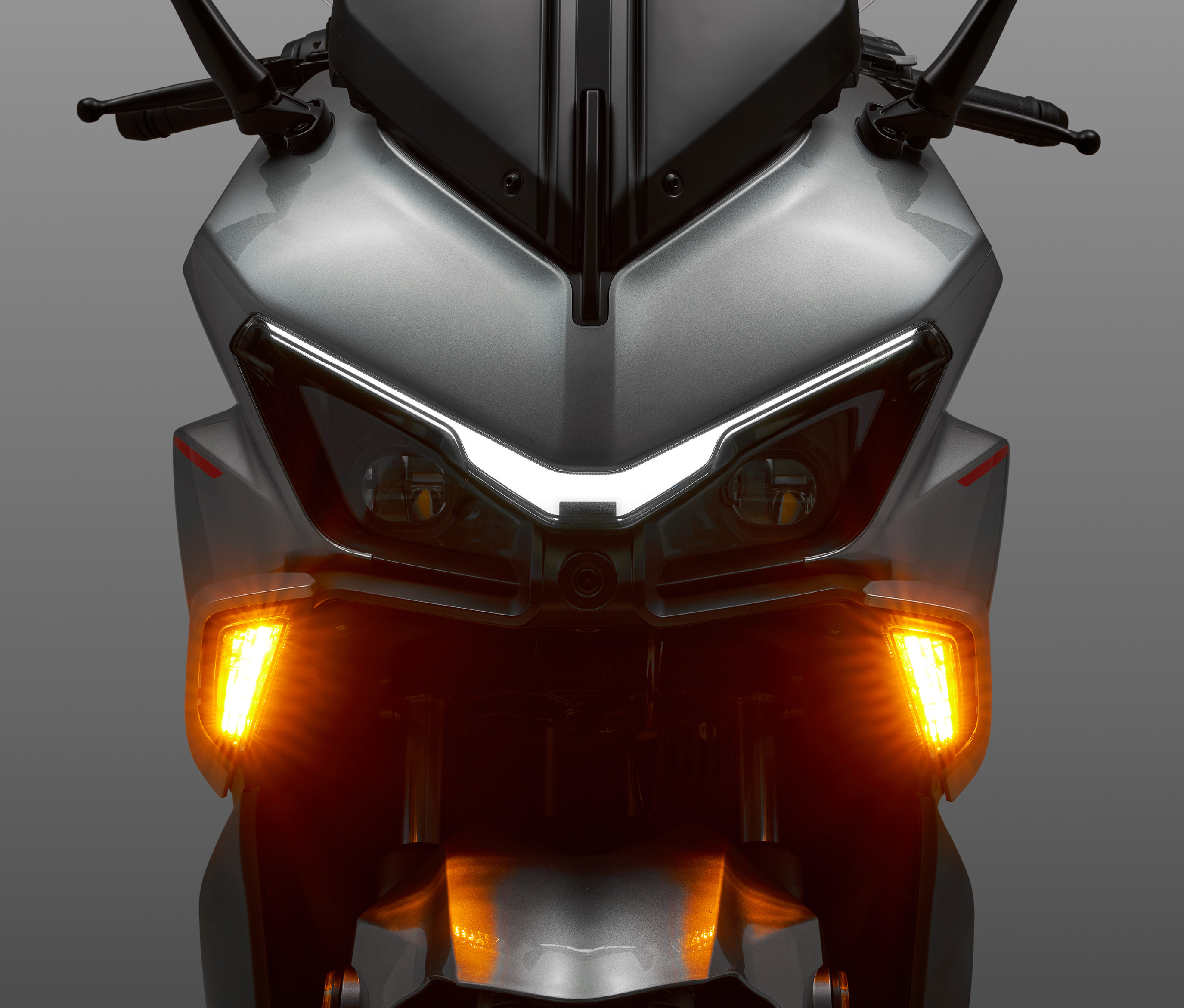 QJMOTOR FORT 125 N: Die Front mit hellem Scheinwerfer und orange leuchtenden Blinkern.