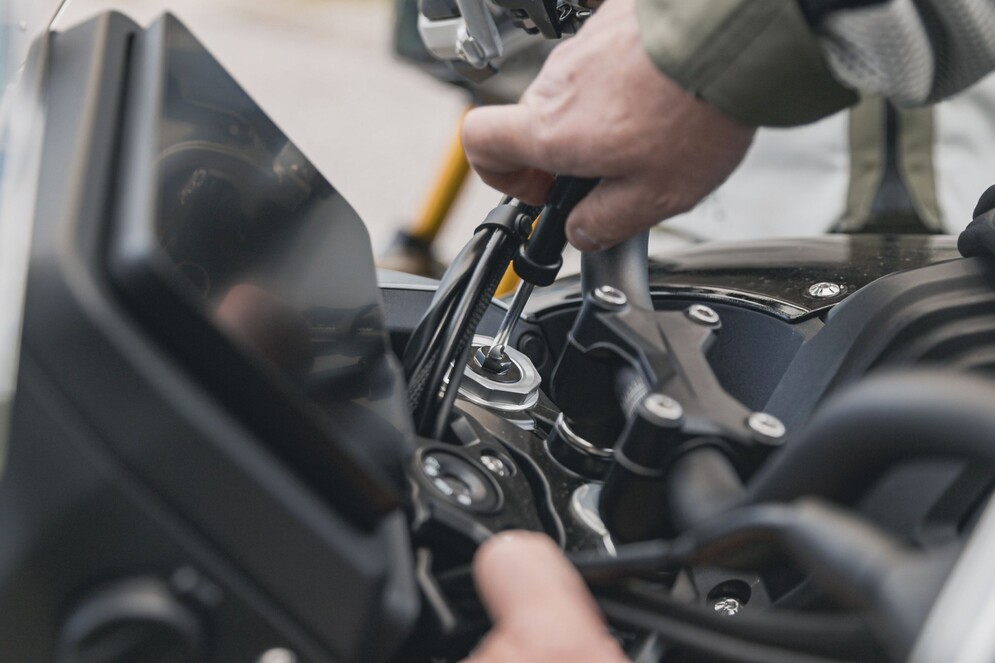 QJMOTOR SRT 700 SX: Eine Hand bei der Einstellung eines Hebels am Lenker des Motorrads.