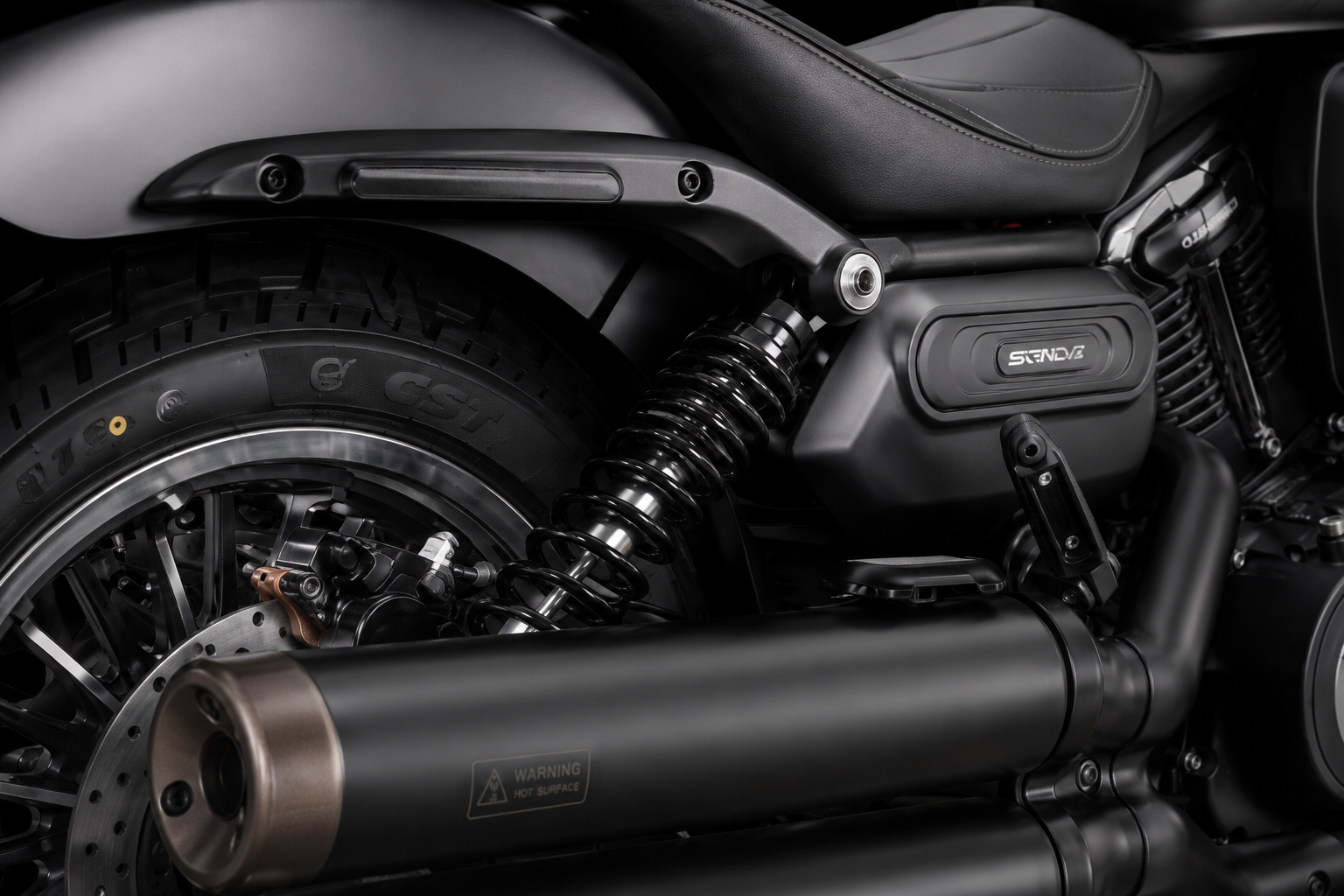 QJMOTOR SRV 600 V2: Ein hinteres Federbein neben Reifen, Schutzblech und schwarzem Auspuff.