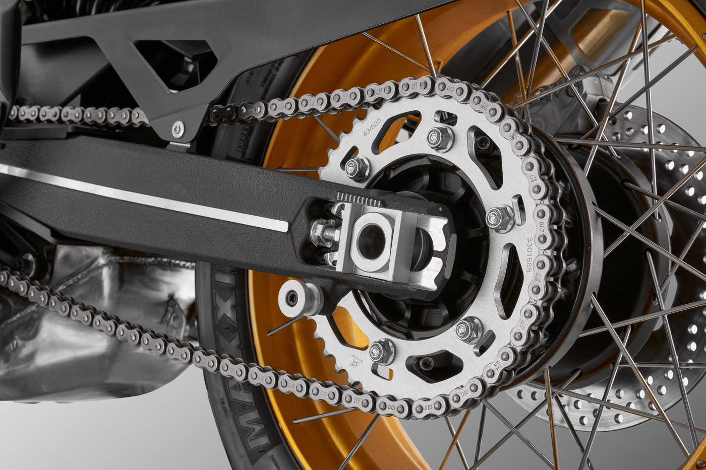 QJMOTOR SRT 900 SX: Kettenantrieb, hinteres Kettenrad, goldfarbene Felge und Achsaufnahme.