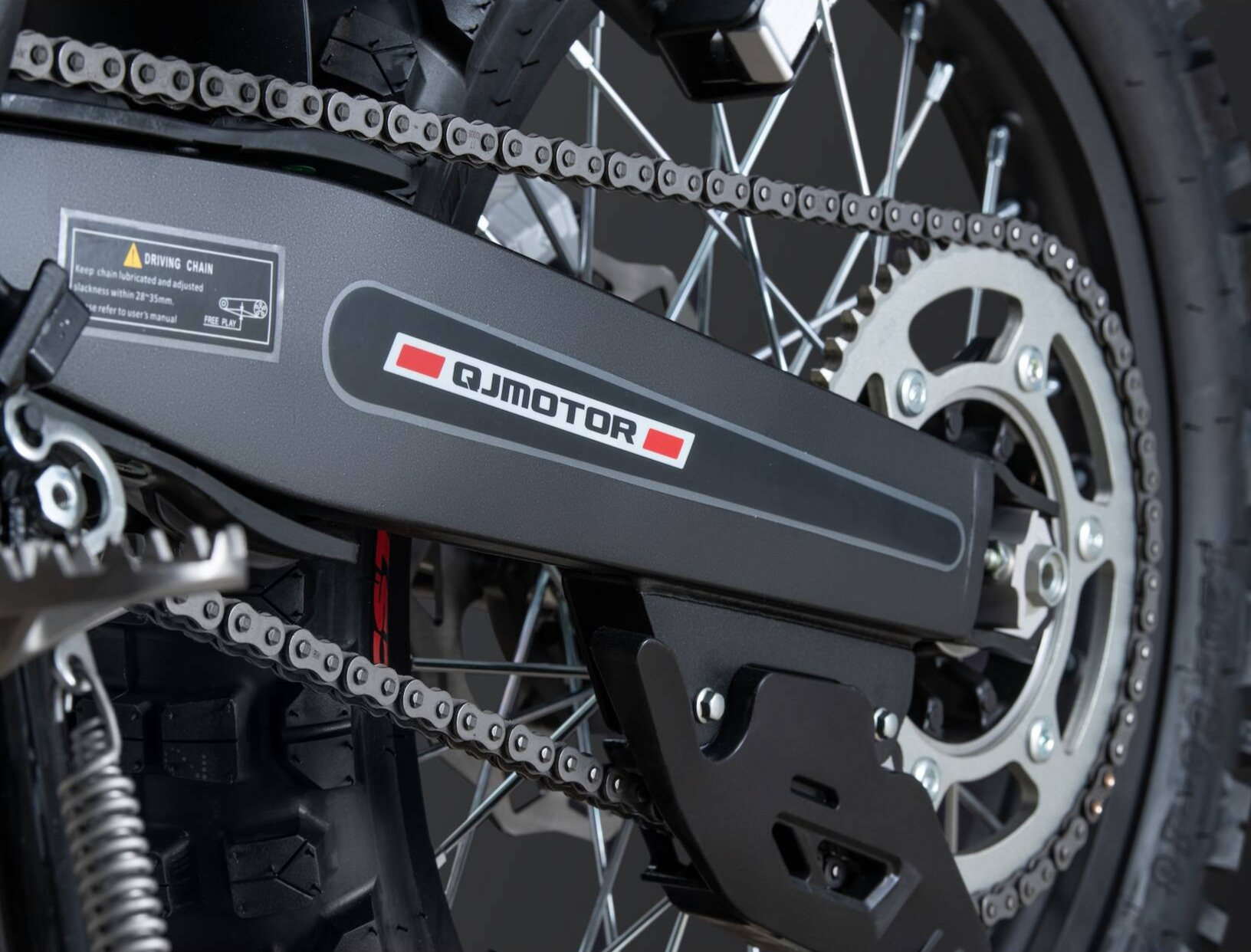 QJMOTOR COV 125 X: Der Kettenantrieb am Speichenhinterrad mit Schwinge und sichtbarem Kettenrad.