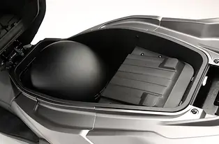 QJMOTOR MTX 125: Nahaufnahme der mit einer runden Schutzkappe versehenen USB-Anschlussstelle.