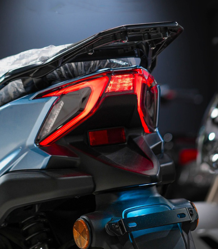 QJMOTOR RKO 50: Das rot leuchtende Rücklicht unter dem schwarzen Gepäckträger am Rollerheck.