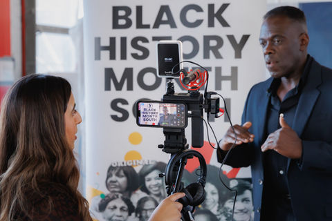 Lou being filmed by and talking to a member of the press for promotional material.