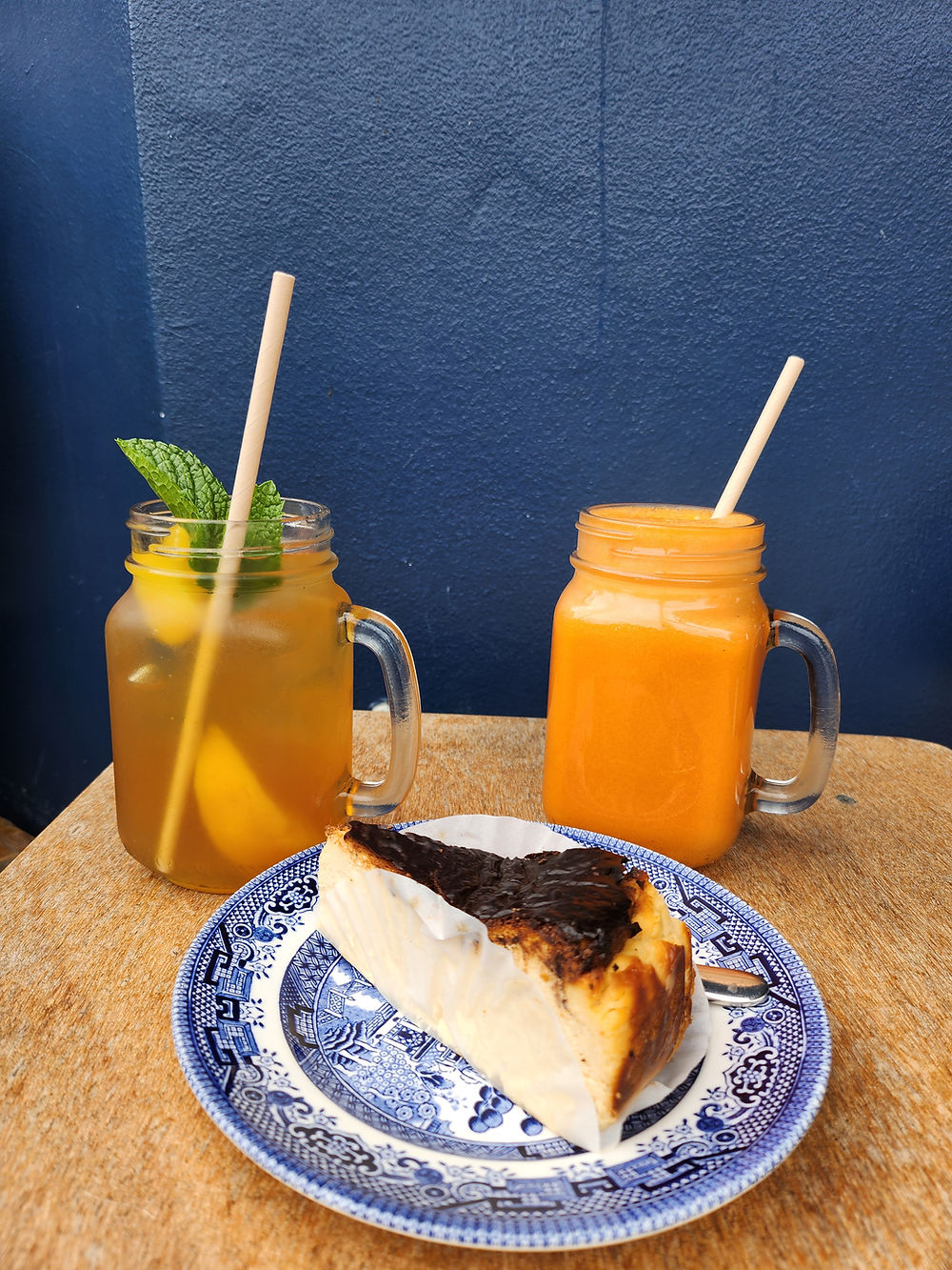 Basque cheesecake slice with iced tea and orange juice in mason jars.