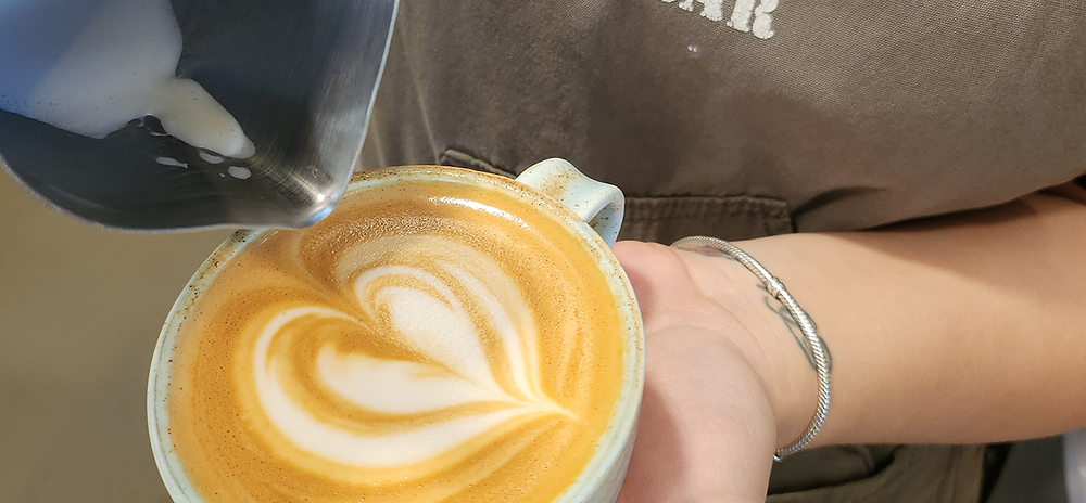 Barista making latte art with a heart design
