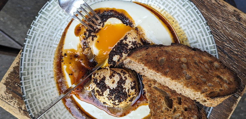 Savory breakfast with runny egg, creamy grits, and organic toast