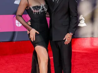 Two elegantly dressed music celebrities pose together on the red carpet at a Grammy Awards event, showcasing stylish formalwear and high-profile glamour.