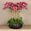 Thumbnail: Artificial Floral Arrangement Centerpiece With Pink Orchids in Black Planter