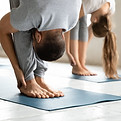 Close up focus on young male master standing in forward bend head to legs position barefoo