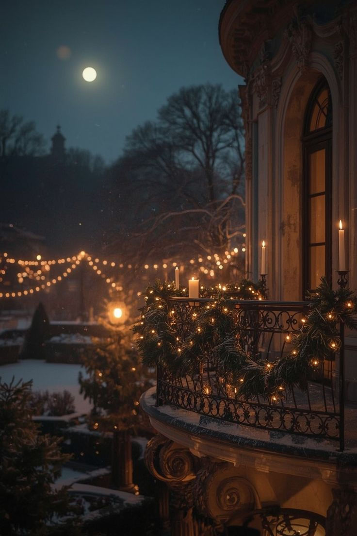 Balcony decorated with garlands and candles on a snowy night. String lights illuminate trees below. Full moon in the clear sky, creating a cozy ambiance.