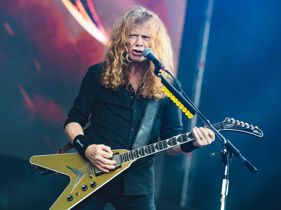 Homem de meia idade tocando guitarra enquanto canta em uma banda de metal