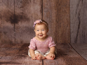 Baby Newborn Photographers Melbourne. Cute Baby sitting on rustic wooden backdrop smiling
