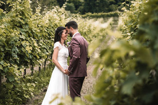 Sposi tra i filari della vigna, lui in abito bordeaux, matrimonio in collina