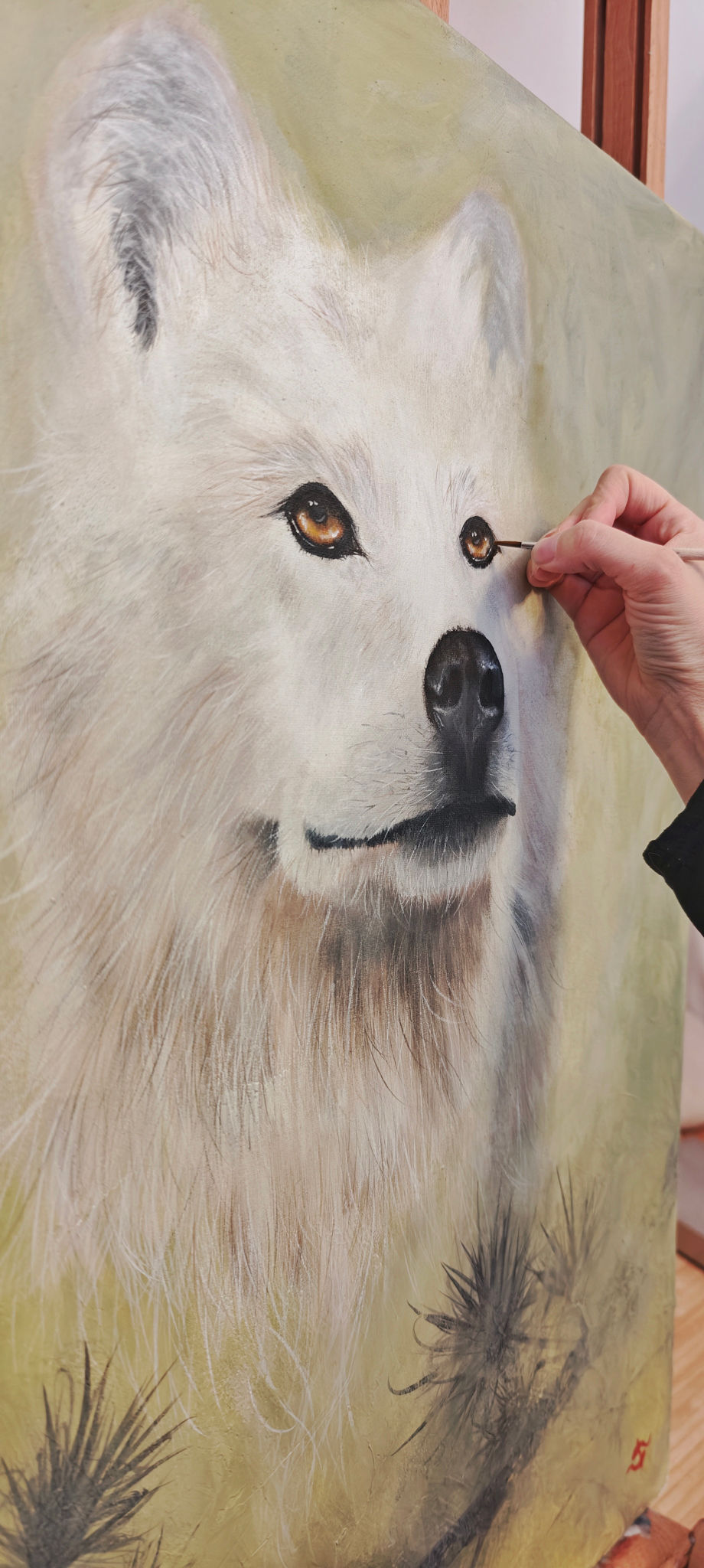 Künstler malt das Auge eines weißen, flauschigen Wolfes auf einer Leinwand; detailreiche Tiermalerei im Atelier.
