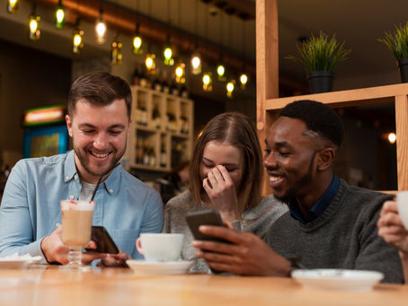Group of friends laughing while looking at a smartphone, symbolizing engagement and community through social media.
