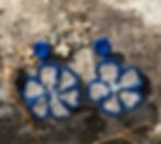 Boucles d'oreilles fleur beige et bleu posé sur une écorce de bois