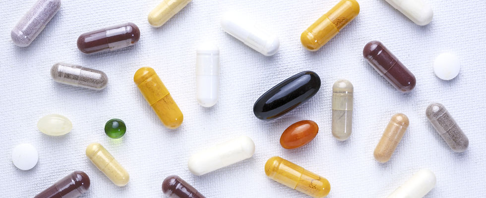 variety of white and colored supplements scattered on white surface