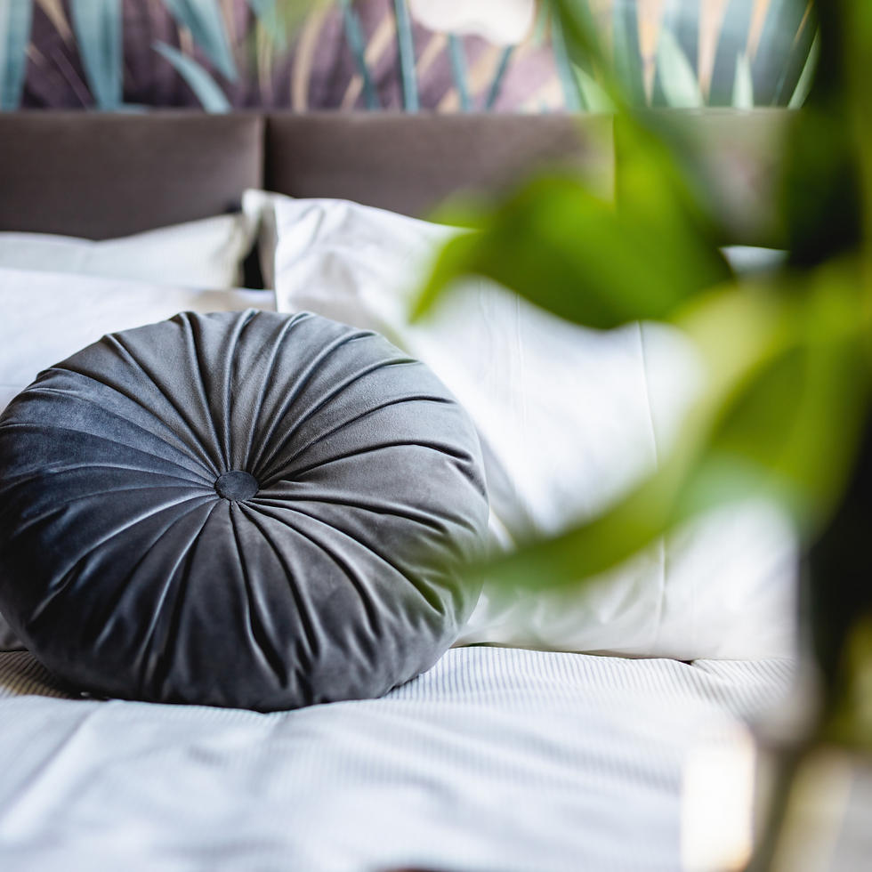 Coussin rond en velours gris sur lit blanc dans une chambre élégante et cosy – décoration d’intérieur par Rachel Intérieurs, architecte d’intérieur en Île-de-France.