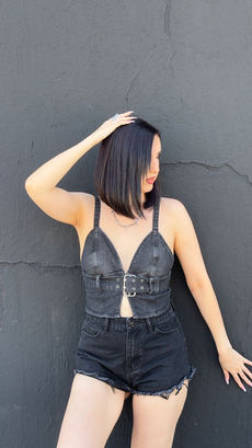 Outfit estivo composto da top in denim nero slavato con fibbia e spalline sottili, shorts in denim con bordo grezzo e ricamo fiamme