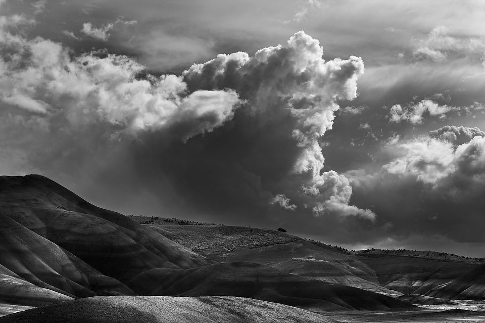 Storm light moves across the Painted Hills as dramatic clouds mirror the land’s layered forms.