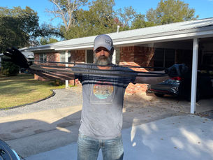Mobile mechanic standing in a driveway holding a stretched, worn-out serpentine belt to show its condition during a vehicle inspection.