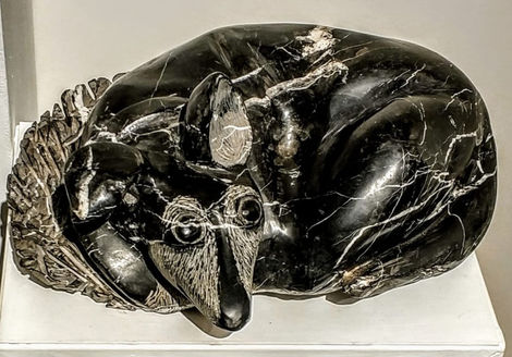 Sculpture of a curled-up black animal figure.