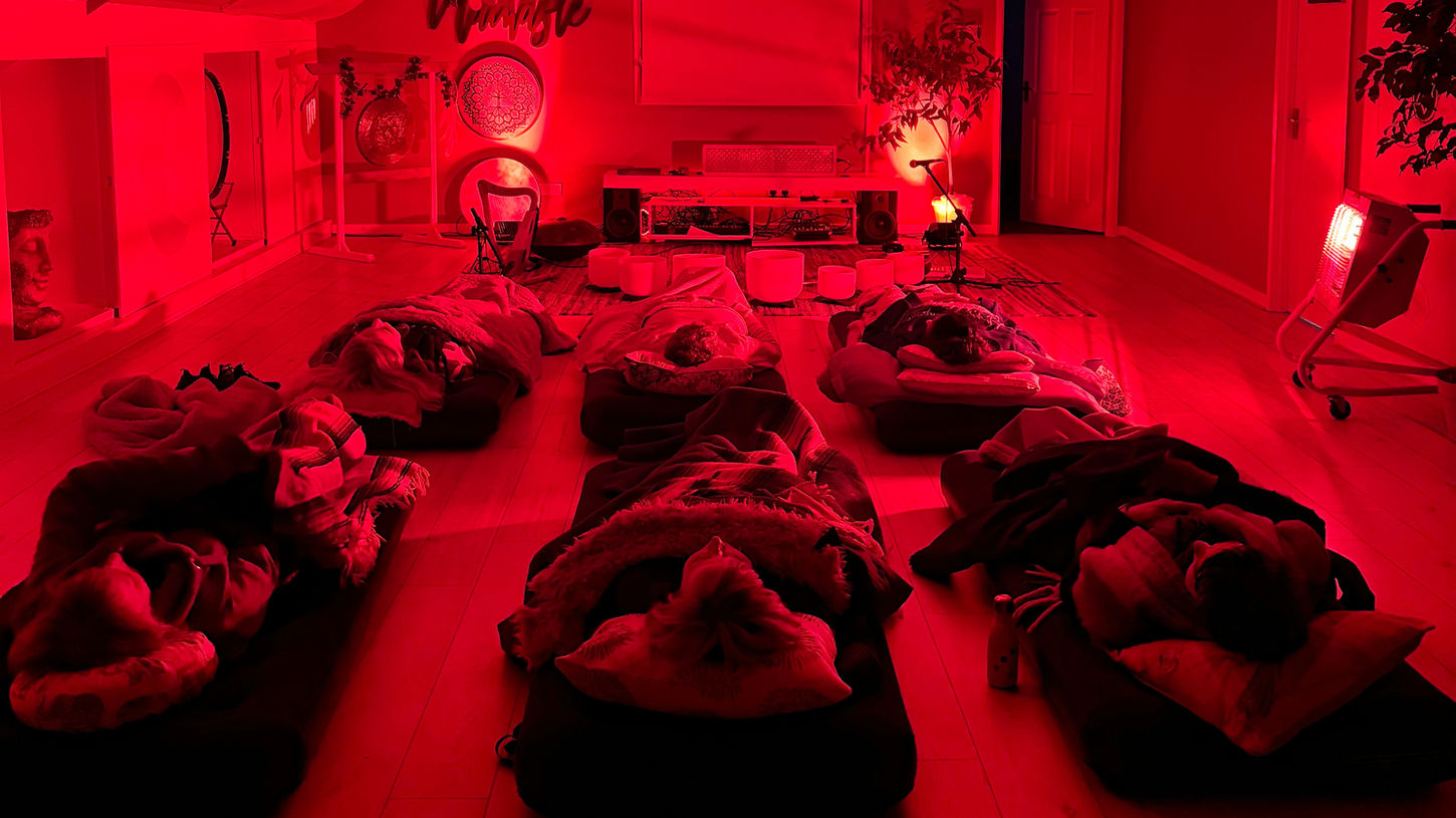 People lying down with eyes closed, immersed in a sound meditation session.