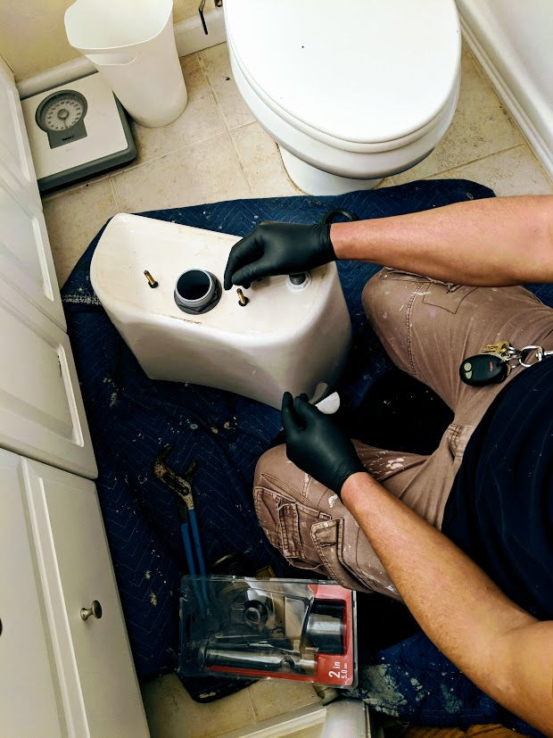 plumber doing toilet tank repair